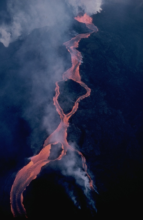 A lava flow from the Mauna Loa NE rift zone travels down the eastern flank on 30 March 1984. The flow developed a braided morphology as it moved around topographic highs. These flows originated from the easternmost vents of the 1984 fissure that opened during the afternoon of 5 March just below Pu'u 'Ula'ula; that remained the only active vent through to the end of the eruption on 15 April. Photo by J.D. Griggs, 1984 (U.S. Geological Survey).