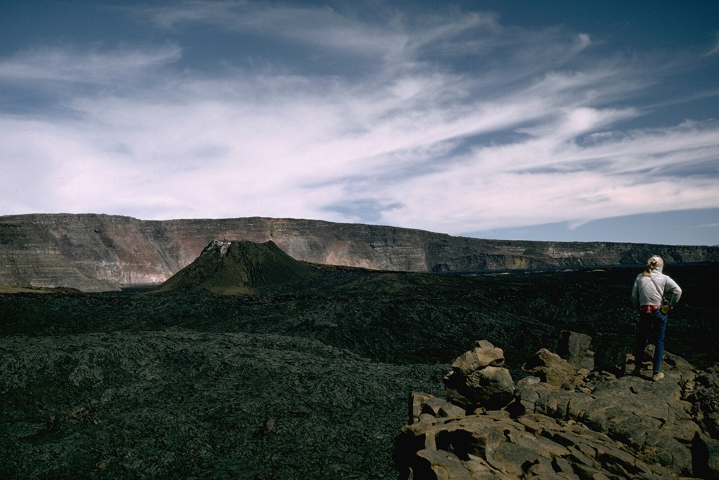 The spatter cone that formed during the 1940 eruption of Mauna Loa is seen in Moku'aweoweo caldera in this 1966 view from the southern rim of the caldera with the western caldera wall in the background. The eruption began along a 6-km-long fissure that extended across the caldera and down the SW rift zone. Activity soon became focused within the caldera and lava flows covered two-thirds of the caldera floor. Photo by Richard Fiske, 1966 (Smithsonian Institution).