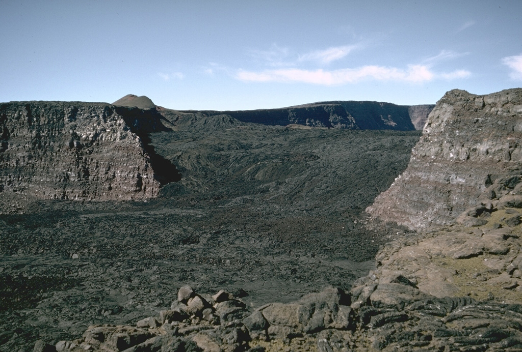 This view looks across Mauna Loa’s South Pit towards Moku’aweoweo caldera in 1966. The lava flows seen here erupted in 1949 within the caldera, then flowed into South Pit after covering the southern caldera floor and continued south for an additional 9 km beyond this crater. The small scoria cone on the horizon was constructed along the main fissure, which fed a lava flow that traveled 11 km down the west flank early in the eruption. Photo by Richard Fiske, 1966 (Smithsonian Institution).