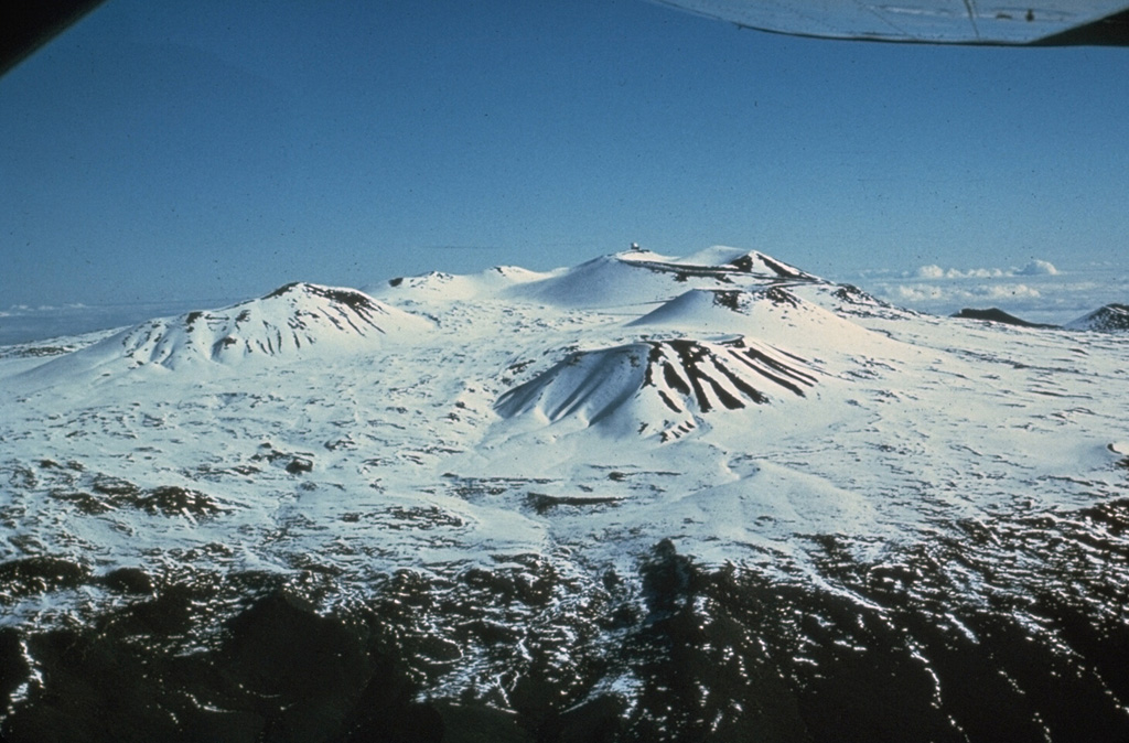 Scoria cones across the snow-covered Mauna Kea summit are some of the most recent features of this volcano, seen here from the SW. The high altitude makes it the only Hawaiian volcano that is known to have had glaciers. Photo by Don Swanson (U.S. Geological Survey).