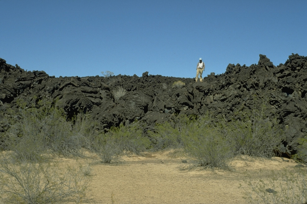 A geologist stands on the irregular surface of a lava flow north of Volcán la Morusa, near Cerro Colorado. The flow is one of many young sparsely vegetated basaltic lava flows of the Pinacate volcanic field. Flow morphologies remain pristine for long periods of time in this arid region. Photo by Jim Luhr, 1996 (Smithsonian Institution).