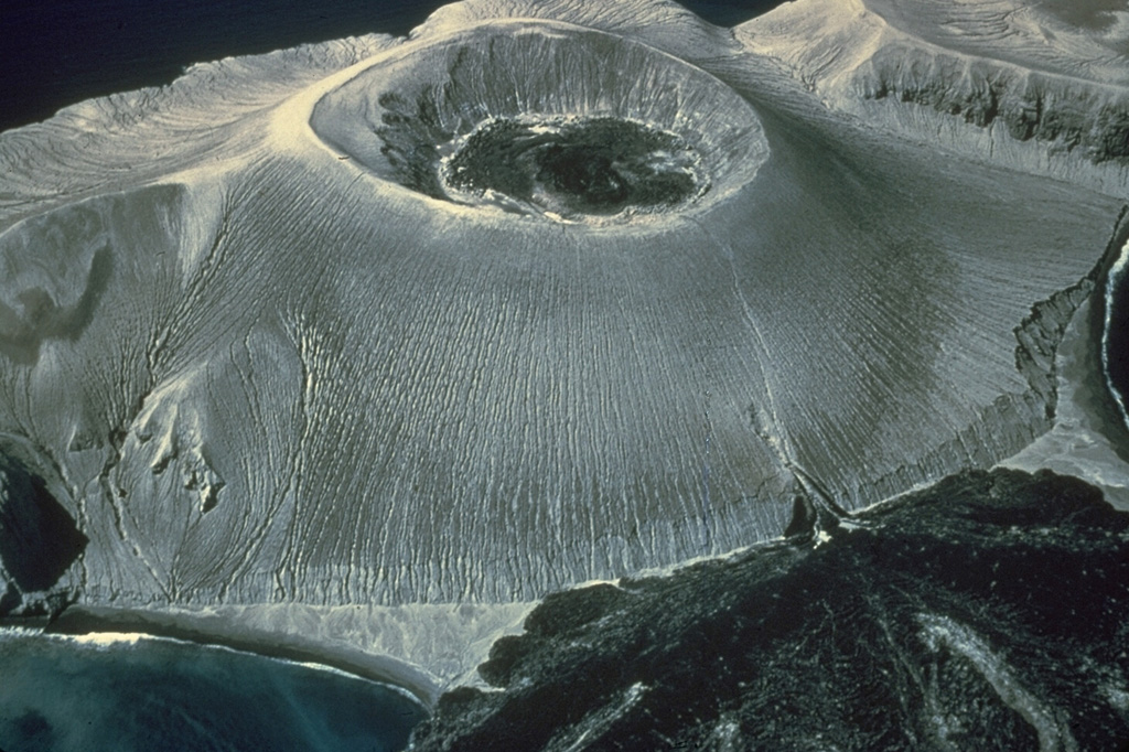 An aerial view from the SE shows the Bárcena tuff cone, constructed during an eruption in the Revillagigedo Islands off the western coast of México during 1952-53. The 700-m-wide crater is partially filled by lava, and the lava delta at the lower right was fed from a vent on the flank. The tuff cone was constructed to a height of about 330 m from near sea level within the first few weeks of an eruption that began on 1 August. Lava was seen in the crater by mid-September and flank lava extrusion began on 8 December. Photo by Adrian Richards, 1955 (U.S. Navy Electronics Laboratory).