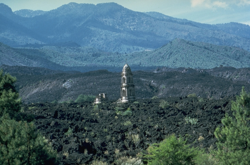 The tower of the unfinished San Juan Parangaricutiro church rises above the lava flows that surrounded it in 1944. The Taquí lava flow began on 8 January 1944 from the SW base of Parícutin. Renewed lava extrusion on 24 April threatened the town of San Juan Parangaricutiro and impacted it 17 June. The church was surrounded by lava in July. By the time the flow ceased in early August it had a length of 10 km. Photo by James Allan, 1985 (Smithsonian Institution).