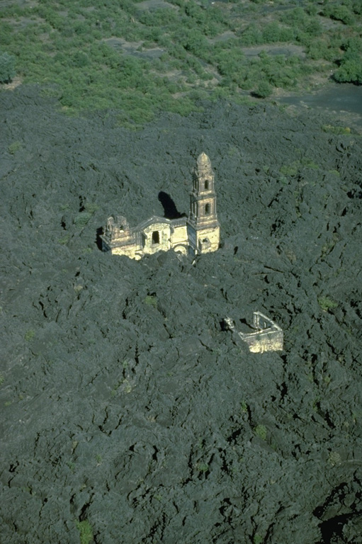The renowned church of San Juan Parangaricutiro was surrounded by lava flows from Parícutin in July 1944.  Only one of the two church steeples had been completed prior to the eruption.  The interior of the church was dismantled only days before it was overrun by the lava flow.  The west margin of the 1944 lava flow appears at the top, with faintly visible abandoned streets of the town beyond.   Copyrighted photo by Katia and Maurice Krafft, 1981 (published in Luhr and Simkin, 1993).