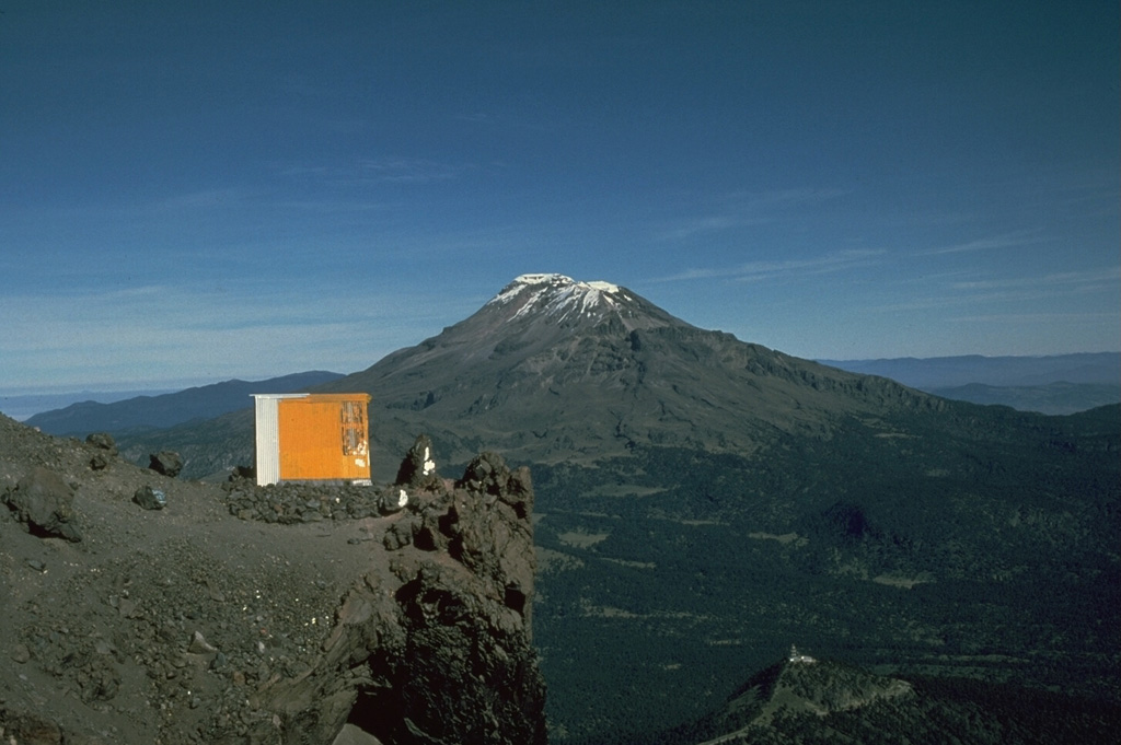The elongate Iztaccíhuatl has a more conical profile when viewed from the Querentano hut on Popocatépetl to the south. One of the youngest vents of Iztaccíhuatl produced a lava flow north of the Paso de Cortés saddle between the two volcanoes. The flow traveled 5 km to the east. Photo by Jim Luhr, 1981 (Smithsonian Institution).