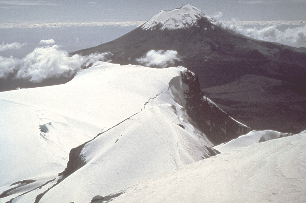 Popocatépetl volcano is seen here to the south from the Iztaccíhuatl summit ridge. Unlike the eroded Iztaccíhuatl volcano, which has been infrequently active during the Holocene, Popocatépetl has been vigorously active. Photo by Jim Luhr, 1981 (Smithsonian Institution).