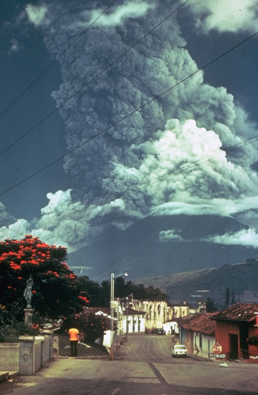 Residents of Antigua Guatemala have observed eruptions at Volcán de Fuego for several centuries. A larger ash plume towers above the city in this October 1974 view of one of Fuego's largest historical eruptions. Pyroclastic flows are also descending the east flank (left). The local topography diverted pyroclastic flows and lahars down drainages to the east and south. Photo by Paul Newton, 1974.