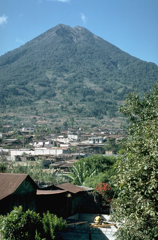 Volcán de Agua towers above the town of Santa María de Jesús on its NE flank. A scarp on the upper north flank extending from the summit crater was the source of a major debris flow in 1541 that destroyed towns on the NW flank. This catastrophe was not accompanied by an eruption. Photo by Lee Siebert, 1988 (Smithsonian Institution).