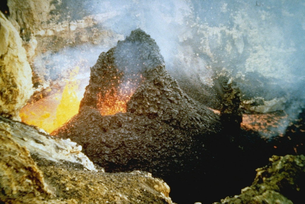 Spatter cones form when blobs of molten lava that are ejected from a vent solidify to form a steep-sided cone. This small spatter cone formed in MacKenney crater of Pacaya volcano in Guatemala on 10 February 1985, during an ongoing eruption that began in 1965. At the time of this photo, the spatter cone was 6-m high, ejecting incandescent volcanic bombs from its vent and extruding lava from its eastern (left) side. Photo by Alfredo MacKenney, 1985.