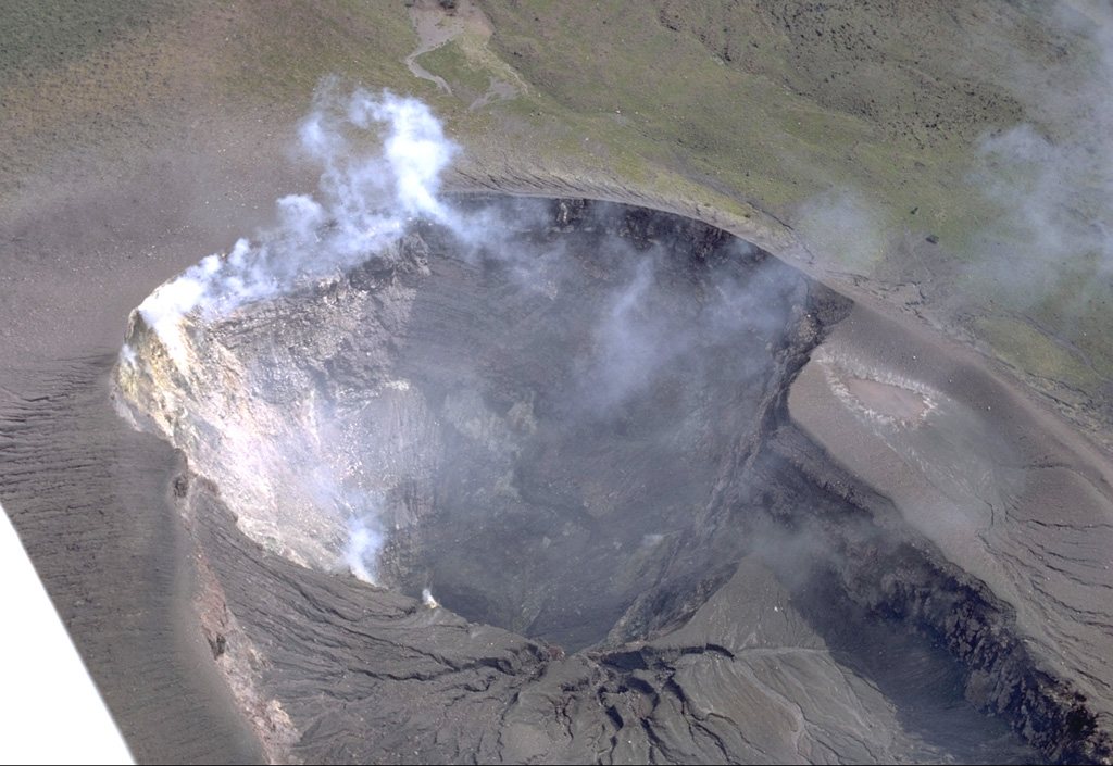 Most recent eruptions of Telica have occurred from the lower NE summit crater.  Fumarolic plumes rise from its floor and just below its rim.  The double summit crater is about 300 x 700 m wide.  Erosional gullies extend into the NE crater from the shallower SW crater.  It lies below the summit, which is out of view below the bottom of the photo. Photo by Robert Citron, 1968 (Smithsonian Institution).