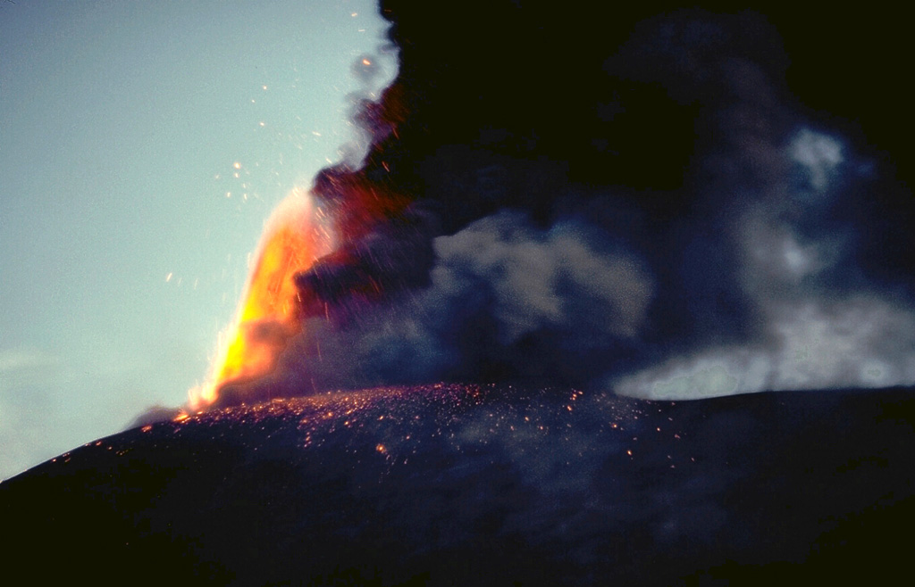 An incandescent lava fountain rises above the summit of Cerro Negro on November 30, 1995, as a plume of dark ash trails off to the right.  Explosive eruptions took place from May 28 or 29 until August 16 and then again from November 19 to December 6.  Incandescent bombs were ejected to 300-400 m above the rim of the 1992 crater on November 21.  The ashfall caused much damage to farmlands.   Photo by Britt Hill, 1995 (Southwest Research Institute).