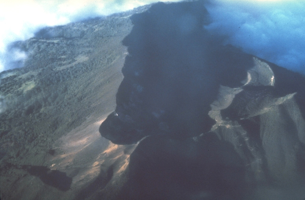 The summit crater complex of 3340-m-high Turrialba volcano appears in the shadow of this aerial view from the south.  Three overlapping craters, each of which contains sub-craters, occur within the 2 x 4 km summit depression.  A cloud bank at the upper right covers the breached NE end of the summit crater complex. Photo by Stan Williams (Arizona State University, courtesy of Mike Carr, Rutgers University).