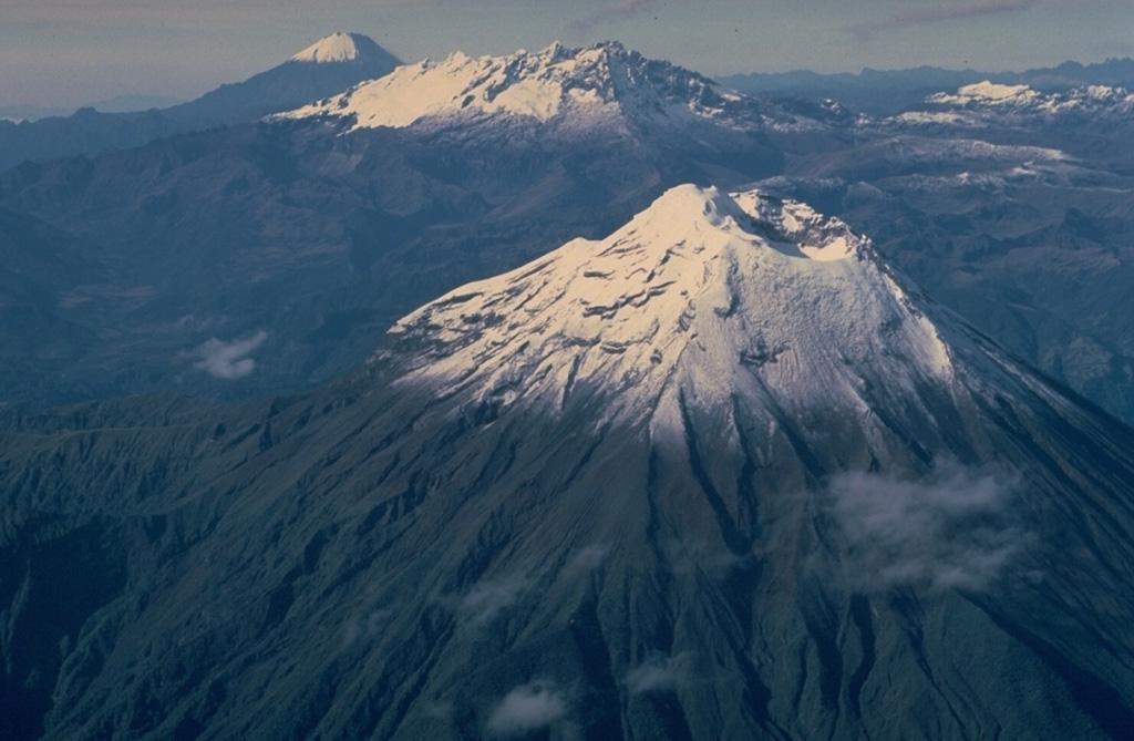 This aerial view looking SSE down Ecuador's Cordillera Real mountain range shows three 5000-m-high stratovolcanoes that have undergone varying degrees of erosion.  Tungurahua volcano in the foreground rises more than 3000 m above its northern base and has produced some of Ecuador's most powerful explosive eruptions during historical time.  Altar (center) is an extensively eroded volcano of Pleistocene age.  Symmetrical, undissected Sangay volcano in the background is Ecuador's most active and has been in continuous eruption since 1934. Copyrighted photo by Katia and Maurice Krafft, 1983.