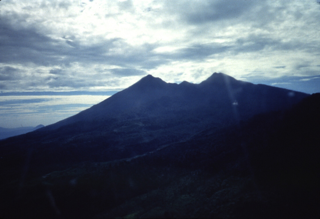 An aerial view from the west shows the profile eroded Salak volcano. Two craters trending SW and NE truncate the summit of the volcano. Anonymous, 1989.