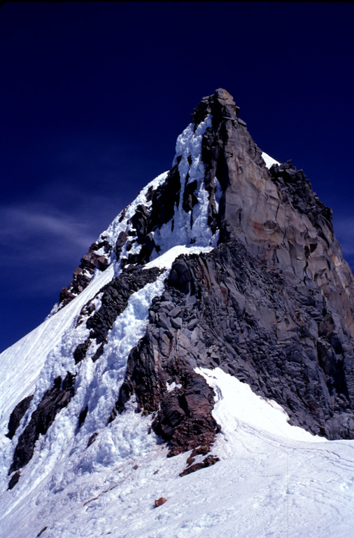 The steep summit pinnacle of Mount Jefferson, seen here from the south, is one of the most dramatic summits of a Cascade Range volcano. Jefferson has been inactive since the late Pleistocene, allowing glacial erosion to remove much of the original summit and exposing the more erosion-resistant rocks that cooled slowly in the central conduit. Photo by Lee Siebert, 1996 (Smithsonian Institution).