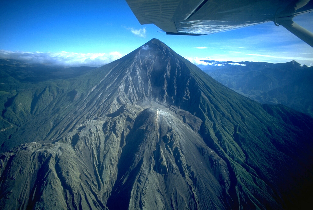 Santa María volcano is seen here in November 1994. The upper SW flank has a 1-km-wide crater formed during a catastrophic eruption in 1902. Two decades later the Santiaguito lava dome began growing at the base of the crater, forming the elongate ridge below the summit and to the left. Since 1922 the Santiaguito dome complex has exhibited frequent explosive activity accompanying episodic periods of dome growth and lava extrusion. Copyrighted photo by Stephen O'Meara, 1994.