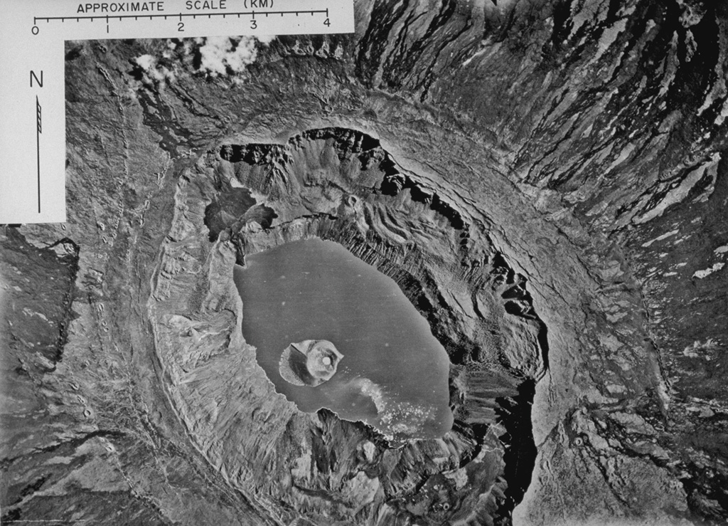 An aerial photograph mosaic shows Fernandina caldera from above in 1947.  Concentric rows of circumferential fissures that are prominent along the caldera rim fed dark lava flows down the outer flanks of the volcano.  The caldera lake that surrounds a prominent tuff cone was destroyed by lava flows during an eruption in 1958, but had reappeared prior to caldera collapse in 1968.  During the 1968 collapse, the caldera floor dropped 350 m.  The tuff cone rode the slow, piecemeal collapse downward without fragmenting.   Photo by U.S. Air Force, 1947 (published in Simkin and Howard, 1971).
