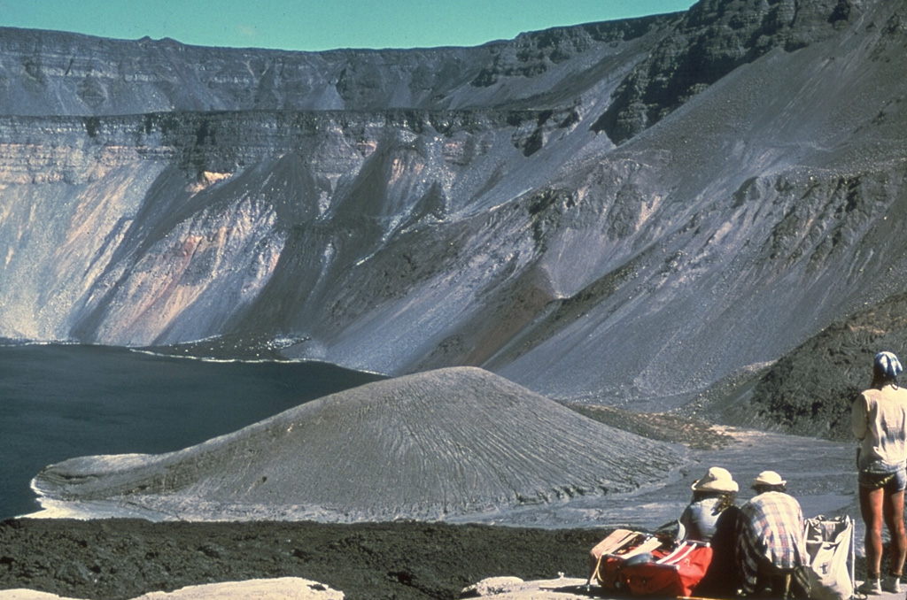 The tuff cone at the lower center, seen here from the NW in 1978, dropped 280 m during collapse of the Fernandina caldera floor in 1968.  Collapse occurred in a piecemeal fashion over a period of about two weeks and the 110-m-high tuff cone, which previously formed an island in the caldera lake, rode the collapse downward without fracturing.  The tuff cone was later buried by a 1991 lava flow following a 1988 debris avalanche.  The prominent SE caldera bench is seen at the far side of the roughly 1-km-deep caldera. Photo by Chuck Wood, 1978 (Smithsonian Institution).