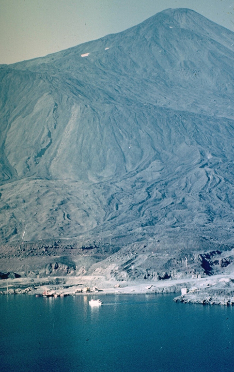 Antuco volcano rises dramatically above the shores of Laguna de la Laja.  Edifice failure at the beginning of the Holocene created a large horseshoe-shaped caldera whose NW rim forms the ridge descending diagonally across the photo to the right.  The steep-sided modern basaltic cone has grown 1000 m since then, producing fresh-looking lava flows with prominent levees that have overtopped the caldera rim and reached the lake shore in the foreground.  The most recent eruptions of Antuco occurred during the 18th and 19th centuries. Photo by Hugo Moreno (University of Chile).