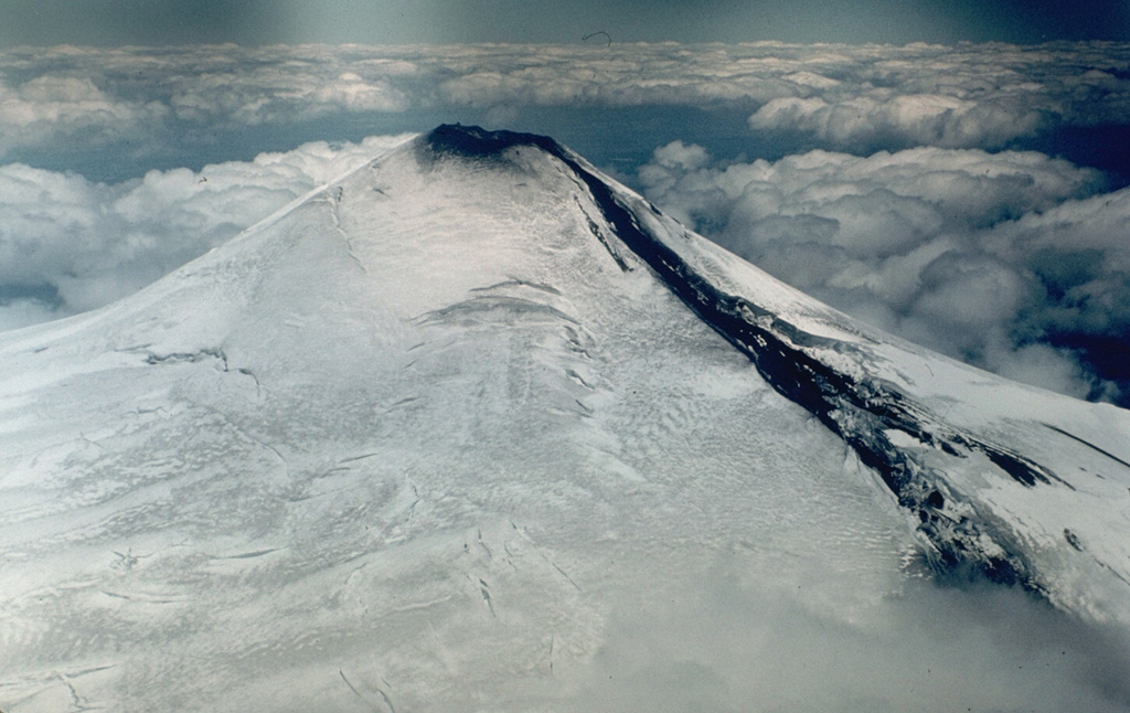 A lava flow descends the NE flank of Villarrica volcano in 1984.  A small lava lake at the NNE side of the summit crater fed lava flows through a notch in the crater rim left by the 1971 eruption.  The lava initially flowed down the summit icefield and then burrowed under the glacier.  The flow emerged onto the surface on November 13, producing a 3-km-long avalanche of lava blocks, ice, and snow. Photo by Hugo Moreno, 1984 (University of Chile).