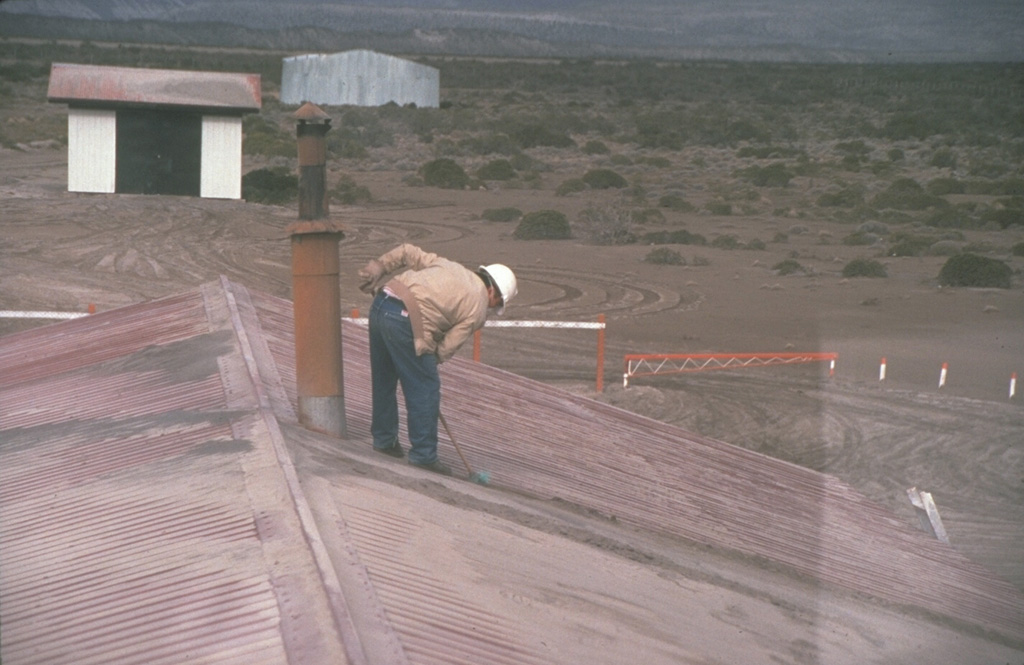 A resident of the Chilean town of Chile Chico, 125 km SE of Hudson volcano near the Argentinian border, sweeps ash from a rooftop on August 23, 1991.  One of the world's largest eruptions of the 20th century took place August 12-15, 1991.  It produced heavy ashfall across Argentina, damaging airport facilities and collapsing roofs of houses near the volcano.  Ash fell as far away as the Falkland Islands, 1000 km to the SE.  The fluorine-rich ash caused extensive mortality to grazing animals across Argentina. Photo by Norm Banks, 1991 (U.S. Geological Survey).