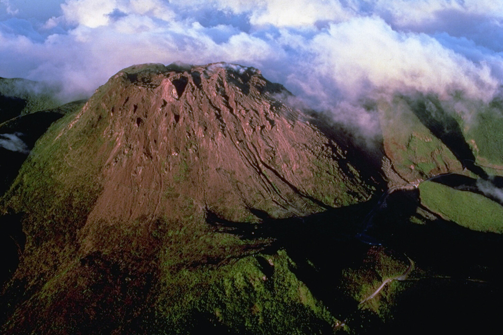 The steep-sided, flat-topped summit lava dome of Soufrière de la Guadeloupe volcano is seen here in a 1981 aerial view from the SW.  The dome was emplaced at the end of a powerful explosive eruption about 500 years ago.  Most historical eruptions have originated from fissures cutting the summit and flanks of the dome.  The 1976-77 eruptions originated from a fissure cutting across the summit from the NW to the SE (right) flank. Copyrighted photo by Katia and Maurice Krafft, 1981.