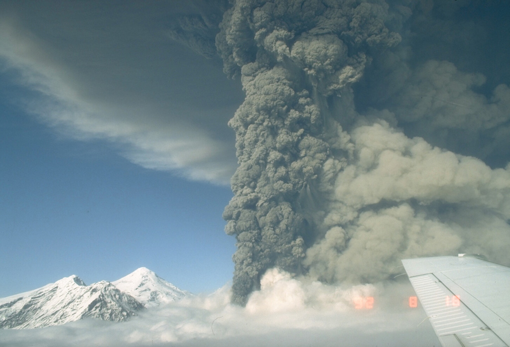 This photo shows an ash plume during the eruption of Spurr on 18 August 1992. A lighter plume rises above pyroclastic flows descending the SE flank to the right, and the summit lava dome complex is to the left. The 18 August event was the second of three brief powerful explosive eruptions in 1992. Photo by Game McGimsey, 1992 (Alaska Volcano Observatory, U.S. Geological Survey).