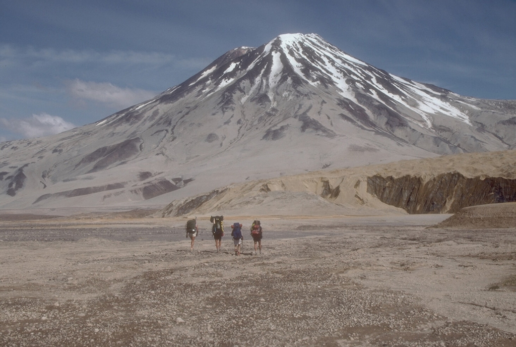 Geologists walk toward Griggs volcano from the base of Knife Creek Glacier to its south. Active fumarole fields persist in the summit crater and along the upper SW flank, and can be heard from the valley floor. The flanks of Griggs and the surface of Knife Creek Glacier have thick ash deposits from the 1912 Novarupta eruption. Photo by Game McGimsey (Alaska Volcano Observatory, U.S. Geological Survey).