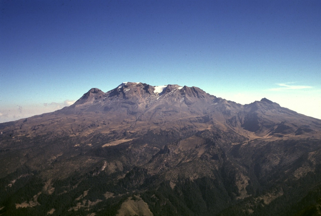 Iztaccíhuatl along with Popocatépetl are the subjects of legends with their morphologies reflecting their characters. The profile of a sleeping woman can be seen here from the west above the Valley of Mexico. A series of overlapping cones constructed along a NNW-SSE trend forms the summit ridge. From left to right they are La Cabeza (the head), El Pecho, Las Rodillas, and Los Pies (the feet). The volcano is mostly Pleistocene in age, but minor Holocene activity has occurred. Photo by Gerardo Carrasco-Núñez (Universidad Nacional Autónoma de México).