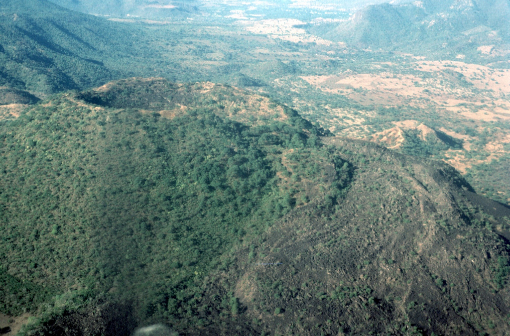 Jorullo scoria cone of the Michoacán-Guanajuato volcanic field is seen here from the ENE. The eruption began with phreatic and phreatomagmatic activity on 29 September 1759 with wet ashfall and lahars that caused damage to neighboring haciendas. By 13 November the cone had reached 250 m in height, and the eruption episode continued until 1774. The sparsely vegetated lava flow to the right was the produced near the end of the eruption. Photo by Jim Luhr, 1997 (Smithsonian Institution).
