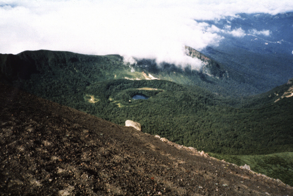 The NishiIwate caldera of Iwatesan is seen here from the summit of Yakushidake, a cone on the eastern caldera rim. Onoshiroko lake fills the Okama crater in the center of the caldera. Photo by Hidenori Togari, 1994 (Hokkaido University).
