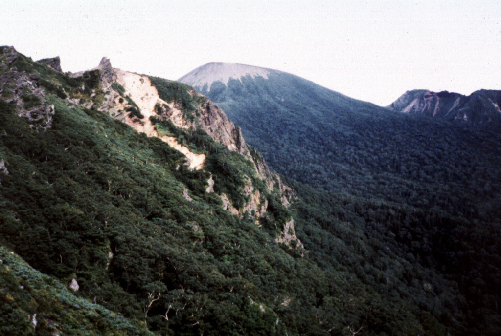 Yakushidake (center) is the summit cone of Iwatesan and was constructed at the eastern end of the 1.8 x 3 km NishiIwate caldera. The N and S caldera rims  form the ridges to the left and right, respectively. Both Yakushidake and a cone in the western caldera have been active in historical time. Photo by Hidenori Togari, 1994 (Hokkaido University).