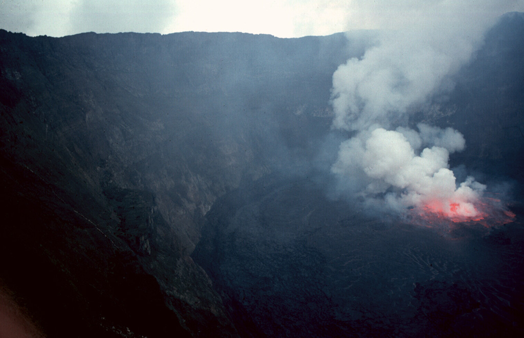A gas plume rises above lava fountains in a lava lake in the summit crater of Nyiragongo volcano on 20 August 1994. Renewed lava-lake activity began the night of 23-24 June 1994 and continued into the fall of 1996. By August 1995 the surface of the lava lake had risen 50 m. Photo by Jack Lockwood, 1994 (U.S. Geological Survey).