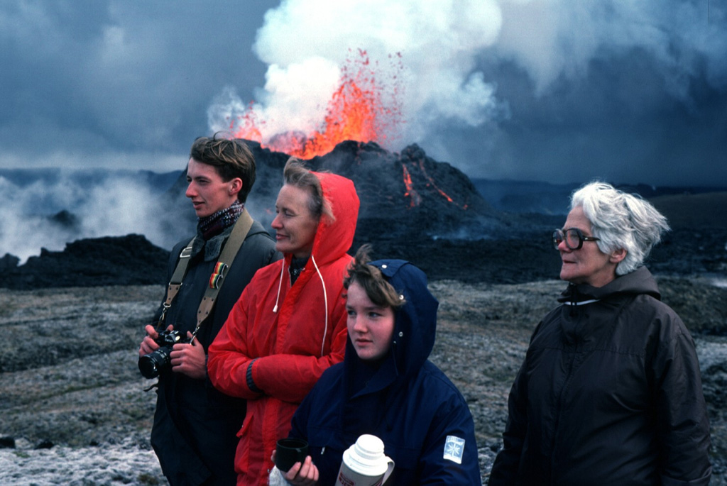 Three generations of an Icelandic family view the 1984 eruption of Krafla volcano as minor lava fountaining can be seen at the spatter cone in the background. The two-week eruption drew visitors from the nearby Myvatn area as well as other parts of Iceland to observe spectacular lava fountaining and slowly advancing lava flows. Photo by Michael Ryan, 1984 (U.S. Geological Survey).