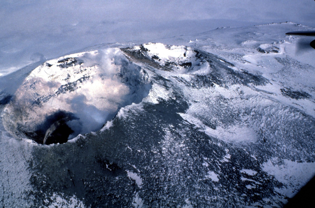 Two summit craters at Erebus are seen in this view, with the 500 x 600 m Main Crater (left) containing an active lava lake (lower left) within the Inner Crater. A smaller inactive crater (center), referred to as Side Crater, is located immediately SW of Main Crater. The smaller West Crater is to the upper right. Photo by Bill Rose, 1983 (Michigan Technological University).