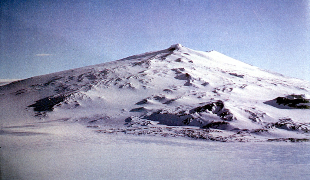 Mount Waesche is the southernmost of volcano of the Executive Committee Range in central Marie Byrd Land. The southwestern flanks seen here are largely ice-free. Scoria cones with a radial alignment are present, along with outcrops dominated by ‘a’a lavas. A caldera of approximately 2 km diameter is present at the summit. Photo by Oscar González-Ferrán (University of Chile).
