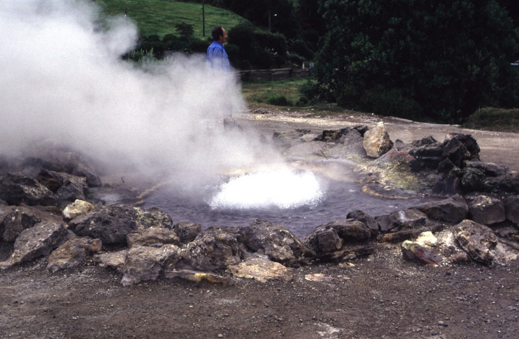 Hydrothermal features at Furnas include several fields of fumaroles, hot springs, bubbling pools and mudpits, and the emission of carbon dioxide both at springs and through the soil. Fumarole fields are found on the north shore of Furnas Lake, in the river gorge of the Ribeira Quente, the Ribeira Quente village on the coast outside of the caldera, and in the upper Ribeira dos Tambores. A significant fumarole field, including the hot spring seen here, is located in the main fumarole field, Caldeiras das Furnas, in the village of Furnas. Photo by Rick Wunderman, 1997 (Smithsonian Institution).