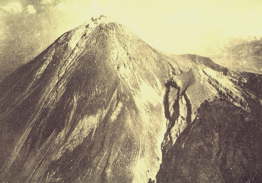 This aerial photo was taken from the SE on 14 August 1922, less than a week after the end of an eruption that began on 18 February 1922. It shows the summit of Merapi prior to a major eruption in 1930, during which much of the summit lava dome collapsed. Eruptions were reported on 18 February, 4-5 April, and 8 August 1922, during which frequent rock avalanches accompanied lava dome growth. A lava flow that traveled 180 m down the western flank is visible to the left. Photo published in Taverne, 1926 