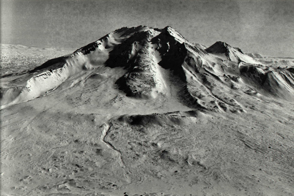 The western side of Taunshits contains a large horseshoe-shaped crater that formed about 8,000 years ago during an eruption that produced a debris avalanche and directed blast similar to that at Mount St. Helens in 1980. A viscous lava flow (center) erupted after the collapse from a vent at the top of the collapse scarp. Photo by Nikolai Smelov, 1998 (courtesy of Vera Ponomareva, Institute of Volcanic Geology and Geochemistry, Petropavlovsk).