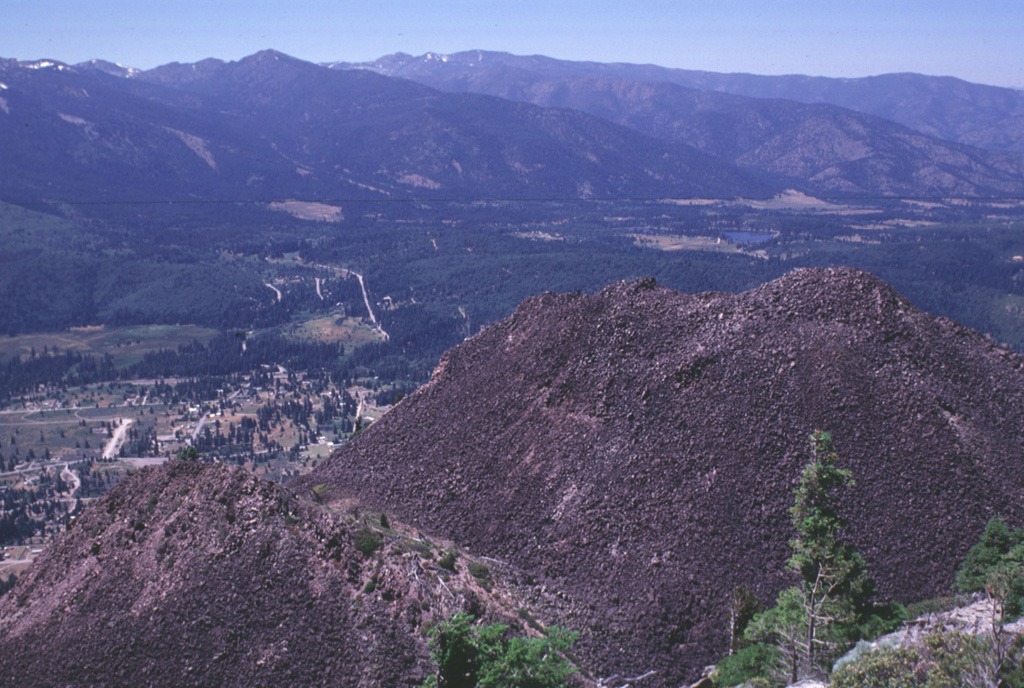 Four overlapping dacite domes form the Black Buttes lava dome on the lower western flank of Mount Shasta. This view looks NW from the summit of Black Buttes, at the tops of two of the domes with the outskirts of the town of Weed below. Pyroclastic flows accompanying formation of Black Buttes extend 10 km S and 5 km N, and underlie currently populated areas. Photo by Lee Siebert, 1998 (Smithsonian Institution).