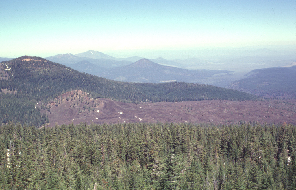 This view from Prospect Peak shows perhaps the youngest lava flow immediately north of the Lassen volcanic center.  This sparsely vegetated flow originated from a small cinder cone (left-center) between Prospect and West Prospect (upper left) peaks, two young basaltic lava cones straddling the NE border of Lassen Volcanic National Park.  The young, but undated andesitic flow traveled initially to the NE and then around the flank of West Prospect Peak to the NW. Photo by Lee Siebert, 1998 (Smithsonian Institution).