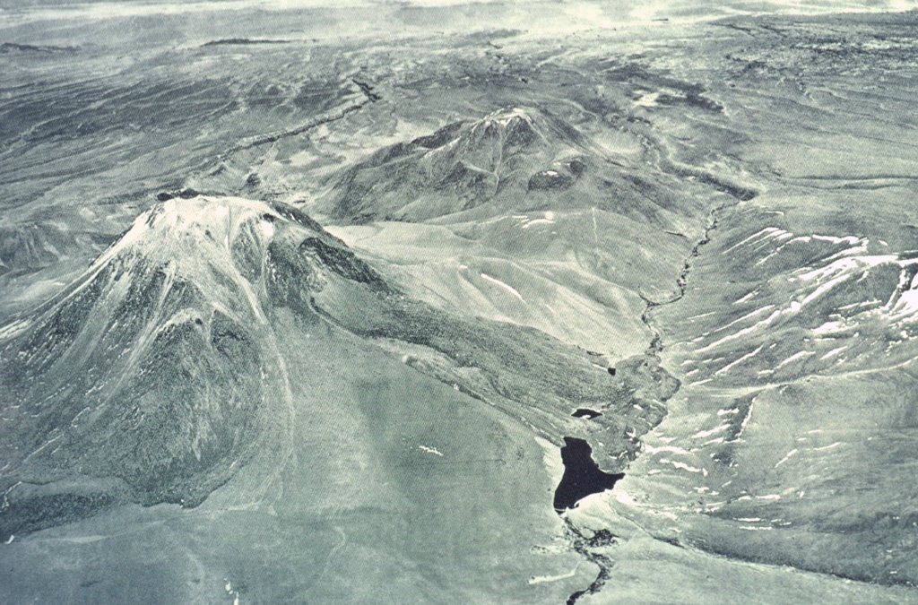 Laguna Verde (left-center), a 5464-m-high stratovolcano located west of Colachi volcano, is seen here in an aerial view from the NE.  The andesitic stratovolcano is one of cluster of volcanoes north and east of Lascar volcano.  Collapse of part of the northern upper flank produced a debris avalanche that dammed the Quebrada Portor, forming the small lake in the foreground.          Photo by Insitituto Geográfico Militar, courtesy of Oscar González-Ferrán (University of Chile).