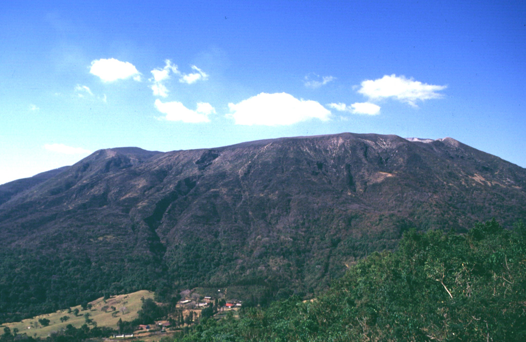 The broad summit of Santa Ana is seen here from Cerro Verde, a cone on its SSE flank. The summit has a series of four nested craters, the largest of which is 1.5 km wide. Houses of Hacienda San Blas are visible at the bottom of the photo. Much of the flanks are covered with coffee crops that are an important part of the local economy. Photo by Carlos Pullinger, 1996 (Servicio Nacional de Estudios Territoriales, El Salvador).
