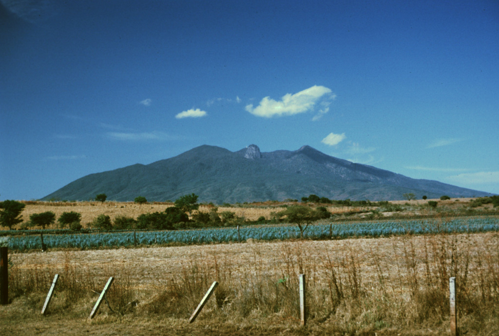 Volcán Tequila is an eroded andesitic-dacitic volcano of Pleistocene age that rises about 1800 m above the surrounding plains.  Tequila is the SE-most of a chain of calc-alkaline stratovolcanoes NW of Guadalajara.  A prominent 300-m-high summit spine, similar to that at Sangangüey volcano, can be seen here in the center of the summit crater, which was been breached to the NE, in the direction of the photo.  The volcano is surrounded by a series of older flank rhyolitic lava domes, obsidian flows, and basaltic cinder cones. Photo by Paul Wallace, 1989 (University of California Berkeley).
