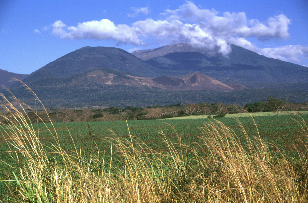 The rounded vegetated peak in the background and to the left is Cerro Verde on the SSE flank of Santa Ana, to the right. The broad edifice in front of them is the Cerro la Olla-Cerro Marcelino scoria cone complex on the Santa Ana flank. Cerro Marcelino at the right side of the cone complex formed during the 1722 eruption, when the Teixcal lava flow traveled 13 km E and destroyed San Juan Tecpan village. Photo by Lee Siebert, 1999 (Smithsonian Institution).