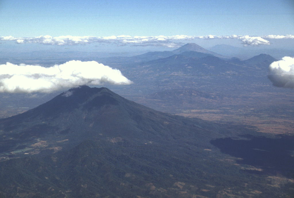 This view to the east across the main El Salvador volcanic front shows San Vicente volcano in the foreground and Tecapa, El Tigre, and Usulután volcanoes to the upper right. The small cone in the saddle between Usulután and El Tigre is Cerro Oromontique. Behind Tecapa and El Tigre is conical San Miguel, and to its right in the far distance is Conchagua volcano. Photo by Lee Siebert, 1999 (Smithsonian Institution).