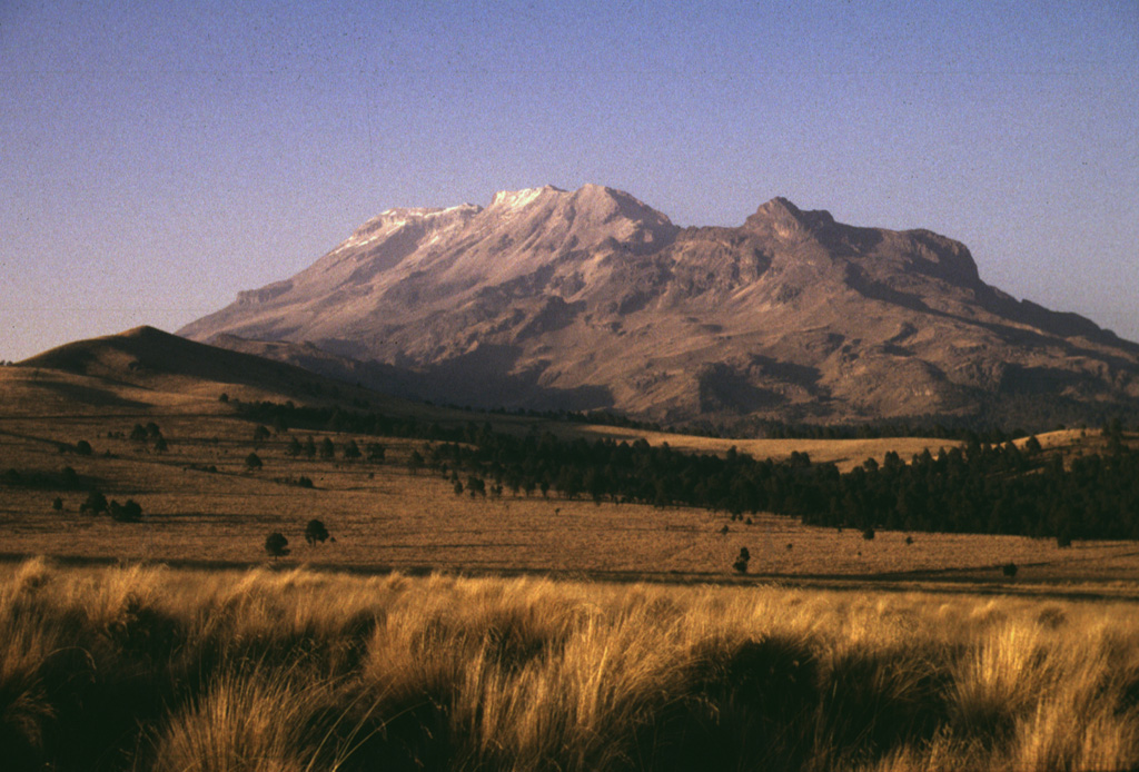The broad Iztaccíhuatl massif rises north of Paso de Cortes, the saddle between Iztaccíhuatl and Popocatépetl volcanoes. The summit of Iztaccíhuatl is at the left, NNW of the apparent high point Las Rodillas (center). The sharp peak at the right is Los Pies (also known as Amacuilecatl), the southernmost major peak of the volcano. Photo by Lee Siebert, 1998 (Smithsonian Institution).