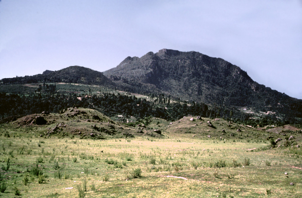 Collapse of the NE flank of the Almolonga Cerro Quemado lava dome about 1,150 years ago produced a debris avalanche deposit with the hummocky terrain in the foreground. An associated lateral blast also swept across the Llano del Pinal, the plain in the foreground. The eruption concluded with the emplacement of a small lava dome inside the avalanche scarp. Photo by Bill Rose, 1989 (Michigan Technological University).