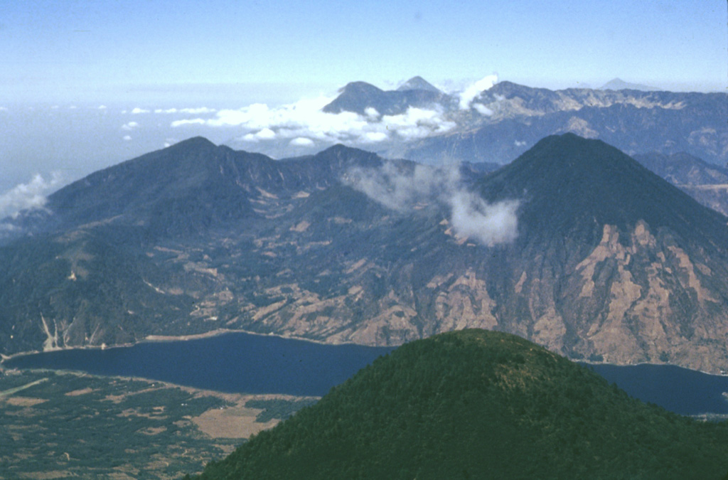 The rounded peak in the foreground is Tolimán volcano. The older post-caldera San Pedro volcano is across Santiago Bay to the right. In the distance are the peaks of Santo Tomás (left) and Santa María (right). Tajumulco volcano is the peak on the far-right horizon. The Guatemalan volcanic front rises more than 3,500 m above the hazy Pacific coastal plain to the upper left. Photo by Bill Rose, 1980 (Michigan Technological University).