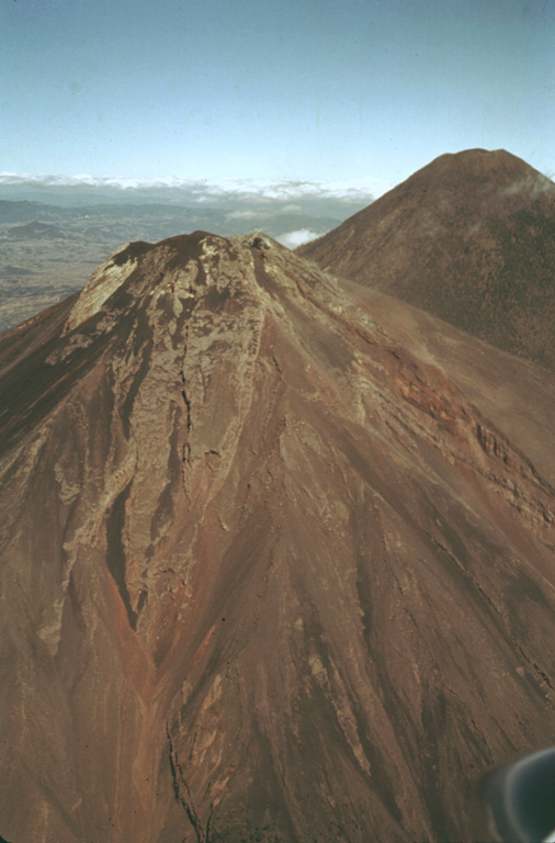 The flanks of Fuego are seen here in an aerial view from the SE in 1978 with Acatenango to the right. Over the formation of these volcanoes the activity began at the northern center, farthest away from the Central American trench (100 km S), and subsequently migrated to the south. Photo by Bill Rose, 1978 (Michigan Technological University).